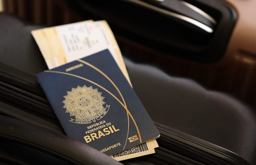 Federative Republic of Brazil passport with tickets lies on touristic suitcase close up in airport waiting hall. Travel worldwide and international tourism concept S