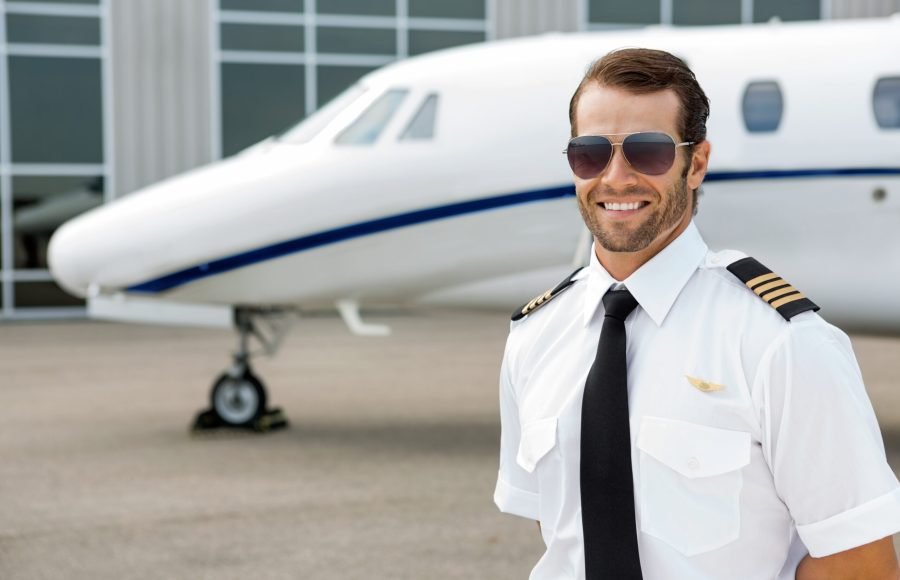 Confident pilot smiling in front of private jet